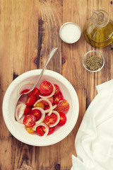 tomato salad with onion in bowl on brown wooden background