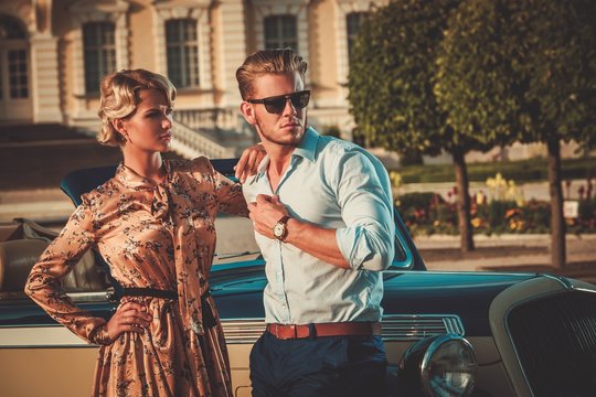 Wealthy couple near classic convertible against royal palace