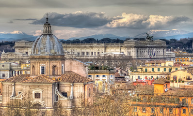 Fototapeta na wymiar Panoramic view of Rome on the background of clouds and mountains. In the foreground the church Santa Maria in Campitelli. In the distance we see the Altar of the Fatherland. HDR