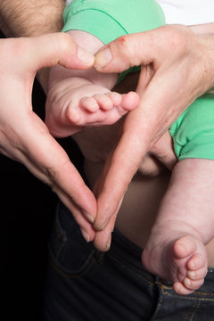 A mother's hands in the shape of a heart around a newborn baby's feet