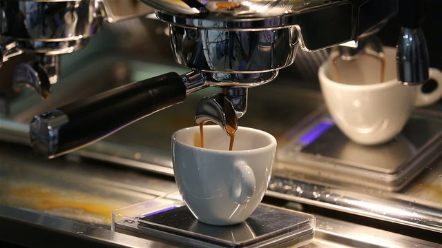 Barista makes coffee in the coffee machine. White coffee mug.