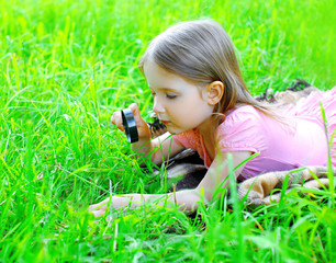 Little girl child looking through a magnifying glass on the gras