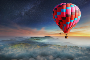 Naklejka premium Colorful hot-air balloons flying over the mountain with with stars. Beautiful mountains landscape with clouds at sunset
