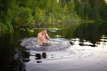 Adult man splash water in forest lake