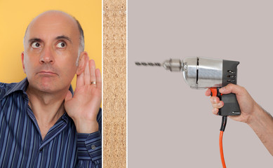 Man leaning against a wall listening to a drill