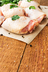 Raw chicken thighs with parsley on wooden table, with copyspace