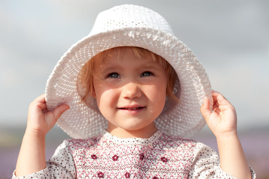 Closeup portrait of baby girl wearing hat outdoors. Smiling child. Childhood. 