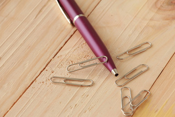 Violet Pen and Paper Clips on Wooden