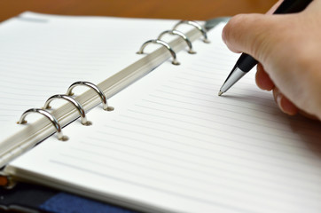 Hand with a pen writing on white paper (Business, Education) - Selective focus