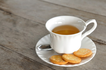 English tea in white cup with cookie on wooden table.