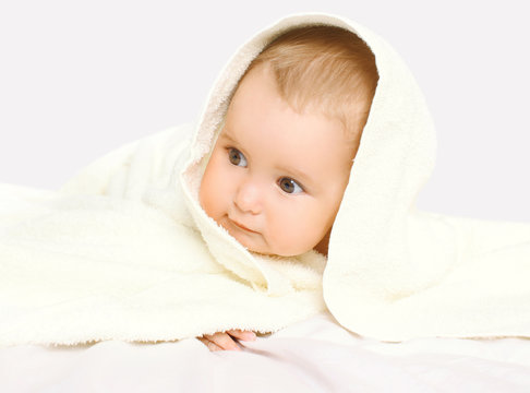 Closeup portrait of baby under towel on the bed at home