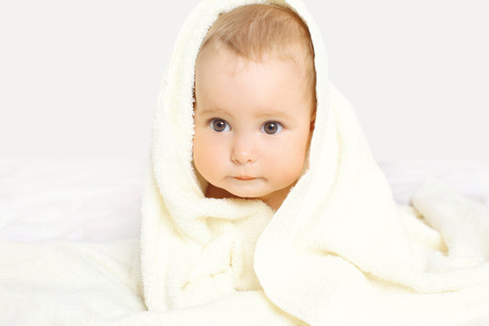 Closeup portrait of cute baby under towel on the bed at home