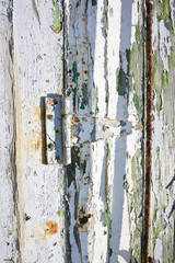 Old hinge of a white wooden door