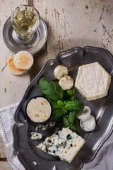 A set of various French and Italian cheeses on the vintage metal