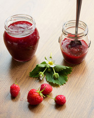 Homemade strawberry jam (marmelade) in jars on wooden background.