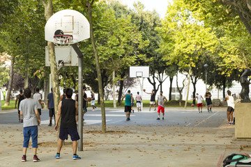 Unrecognizable basketball players on numerous courts on a nice sunny day in a park - 89649201