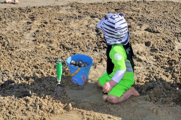 Jeune enfant ramassant des coquillages sur le sable à la mer
