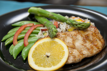 healthy food with grilled chicken, asparagus, lemon slice, snap peas, and rice.