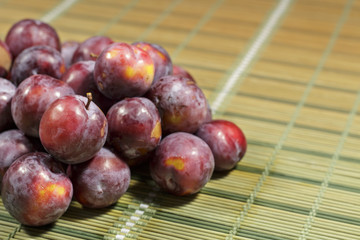 Detail of freshly harvested red plums, with natural wax bloom