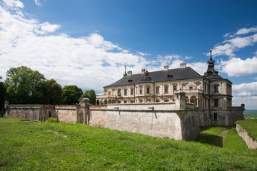 Fototapeta na wymiar Podgoretsky castle with garden and blue cloudy sky background