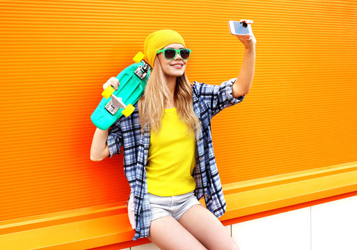 Fashion and technology concept - stylish young girl in colorful