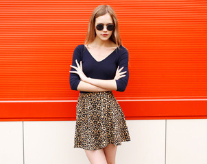 Stylish pretty young woman in leopard skirt and sunglasses over
