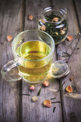 Mug of flavored green tea with rose buds and petals