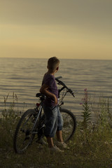 Fototapeta premium boy on a bicycle near the sea in the evening at sunset.