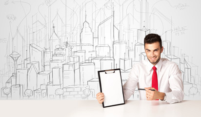 Businessman sitting at the white table with hand drawn buildings