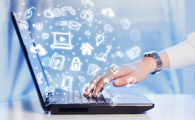 Hand writing on notebook computer with media icons and symbols