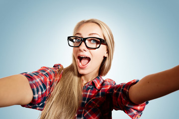 Close up portrait of a young joyful blonde girl holding a smartp