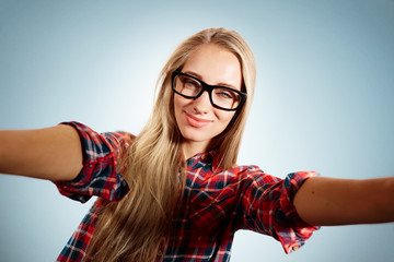 Close up portrait of a young flirting blonde girl holding a smar