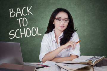 Fototapeta premium Asian teenage student reading book in class