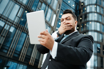 Portrait of handsome surprised business man reads news on tablet