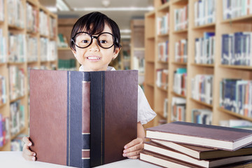 Cute schoolgirl with glasses reading books
