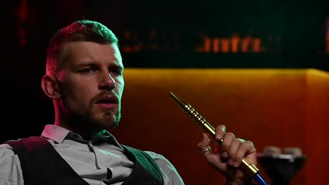 man smoking shisha at restaurant. Slow motion. silhouette