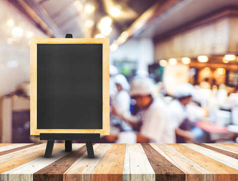 Blackboard menu with easel on wooden table with blur open kitche