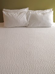 Detail of bed with set of crisp white sheets and pillows    