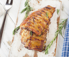 BBQ ribs with herbs on a cutting board.