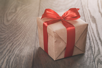 rustic present box with red ribbon on wood table