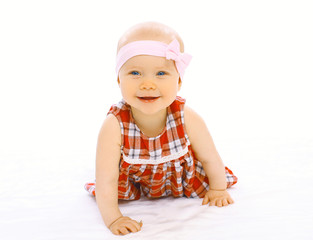 Portrait of cute smiling baby in dress with headband crawls