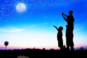 Fototapeta na wymiar Silhouette of father use hand point his son look at full moon on