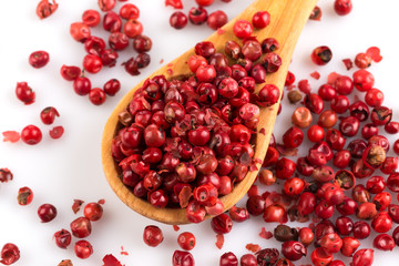 red peppercorns in wooden spoon isolated