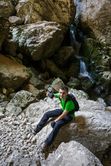 Happy teenager hiking near a waterfall in a cave
