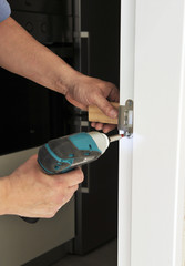 Carpenter screwing the bolt of a door