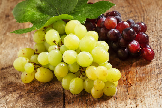 Green and purple round  grapes on old  wooden table, selective f