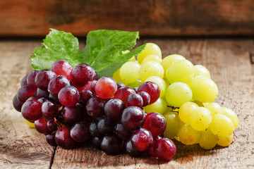 Green and purple round  grapes on old  wooden table, selective f
