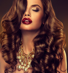 Beautiful model brunette with long curled hair with a large necklace on the neck

