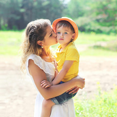 Mother kissing child outdoors in sunny summer day © rohappy