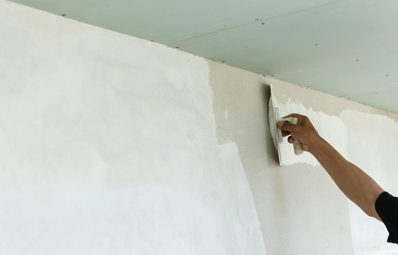Plasterer spreading plaster to wall